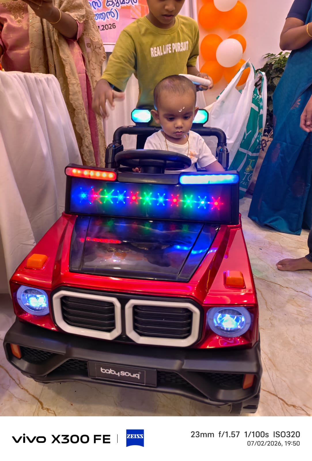 Sanu in a red toy jeep with lights
