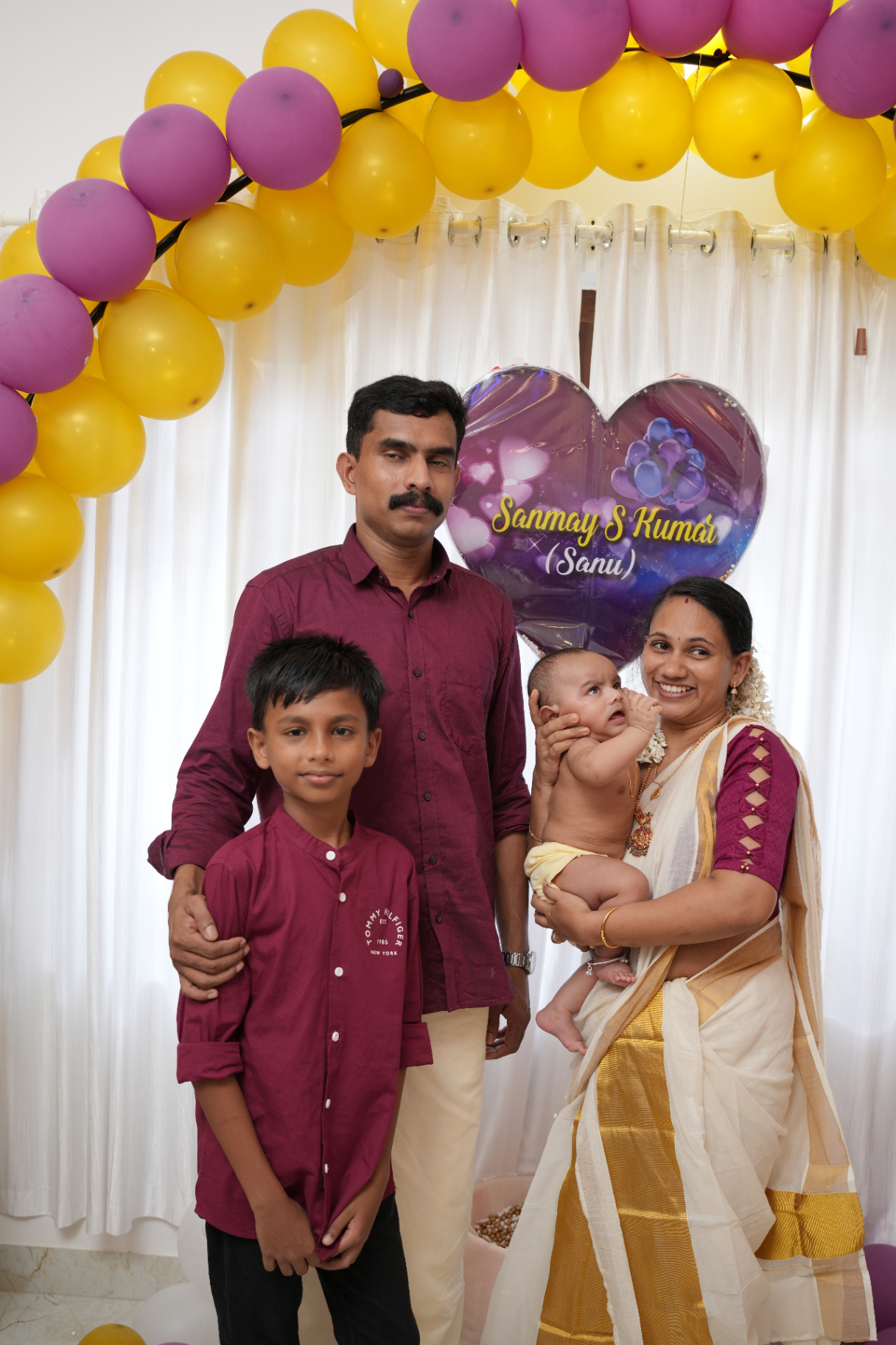 Sanmay with parents and brother by the balloon arch